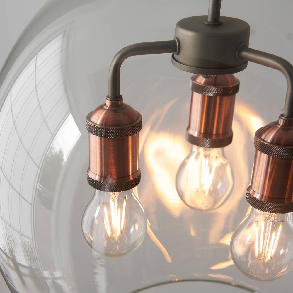 Contemporary industrial-style pendant light with a copper finish and three glass shades for a warm glow.
